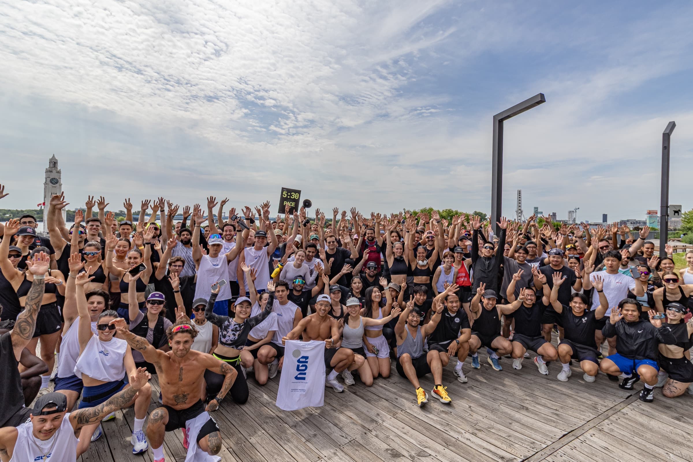 A large group of runners on a boardwalk with their hands in the air